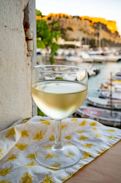 Cassis şarap üretim bölgesinden gelen soğuk beyaz şarap, Fransa, Provence, Cassis 'te renkli tekneleri olan eski balıkçıların limanına bakan terastaki camlarda servis edilir.