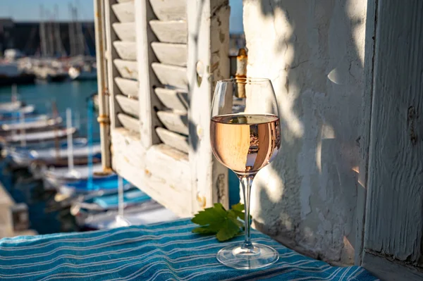 Açık terasta sunulan Rose Provencal şarabı Cassis, Provence, Fransa 'daki eski balıkçıların limanında renkli teknelerle servis ediliyor.