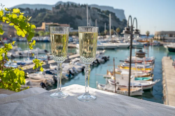 Birthday celebration in summer with two glasses of French champagne sparkling wine and view on colorful fisherman\'s boats in old harbour in Cassis, Provence, France