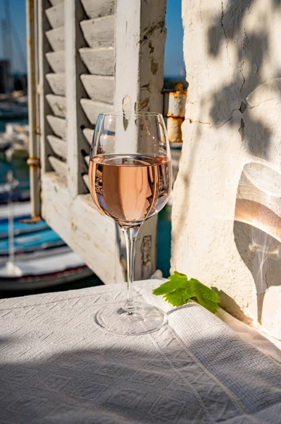 Açık terasta sunulan Rose Provencal şarabı Cassis, Provence, Fransa 'daki eski balıkçıların limanında renkli teknelerle servis ediliyor.
