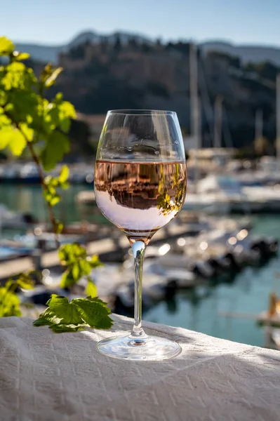 Açık terasta sunulan Rose Provencal şarabı Cassis, Provence, Fransa 'daki eski balıkçıların limanında renkli teknelerle servis ediliyor.
