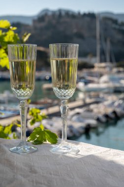 İki bardak Fransız şampanyası, köpüklü şarap ve renkli balıkçı teknesiyle Cassis, Provence, Fransa 'daki eski limanda öğle yemeği.