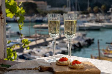 Ekşi krema ve tuzlu somon kırmızısı havyar ve Fransız şampanyası brut köpüklü şarap ile küçük krep çiftleri Cassis, Provence, Fransa 'nın limanındaki renkli teknelerde servis edilir.