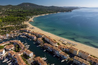 Aerial view on blue water of Gulf of Saint-Tropez, sail boats, houses of Port Grimaud and Port Cogolin, summer vacation in Provence, France