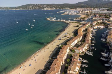 Aerial view on blue water of Gulf of Saint-Tropez, sail boats, houses of Port Grimaud and Port Cogolin, summer vacation in Provence, France