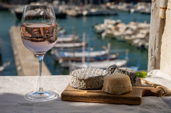 Fransız keçi peyniri crottin ve selles-sur-cher Cassis, Provence, Fransa 'nın limanındaki teknelerde sunuluyor. Peynir, bir bardak kurumuş gül şarabı tadıyor.