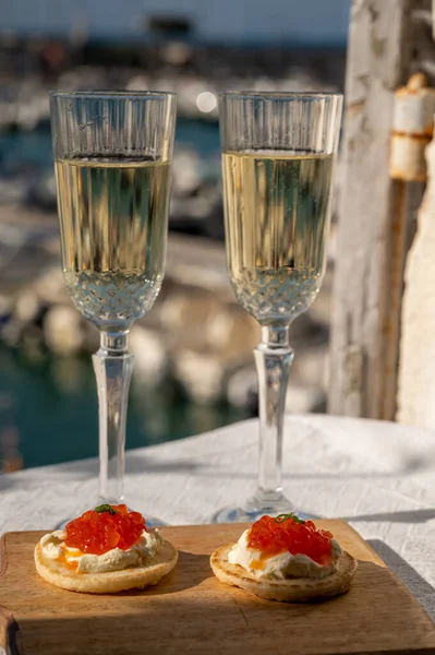 Ekşi krema ve tuzlu somon kırmızısı havyar ve Fransız şampanyası brut köpüklü şarap ile küçük krep çiftleri Cassis, Provence, Fransa 'nın limanındaki renkli teknelerde servis edilir.