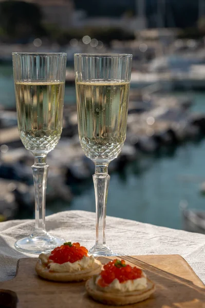 Ekşi krema ve tuzlu somon kırmızısı havyar ve Fransız şampanyası brut köpüklü şarap ile küçük krep çiftleri Cassis, Provence, Fransa 'nın limanındaki renkli teknelerde servis edilir.