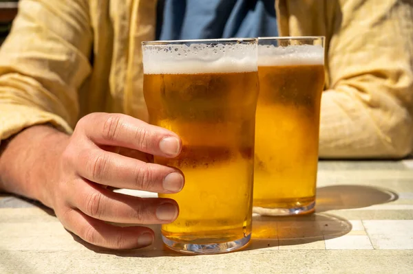 Güneşli yaz gününde Fransız açık hava kafesinde iki bardak taze soğuk bira içen adamlar.