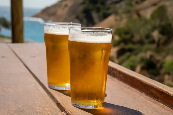 Two glasses of fresh cold lager beer served outdoor in snack bar with view on Calanque de Figuerolles in La Ciotat, Provence, France in sunny day