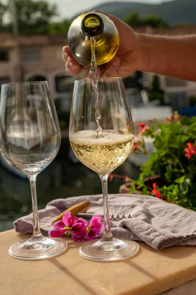 Port Grimaud limanında bir yat limanında soğuk beyaz şarap bardakları doldurmak, Fransa 'nın Provence şehrinde Fransız Riviera' sında yaz tatili