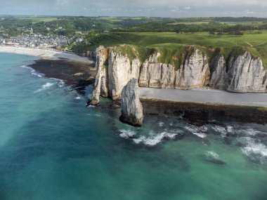 Alçak gelgit dönemi ve okyanusun dibindeki beyaz taşların hava manzarası ve Fransa 'nın Normandiya eyaletindeki Porte d' Aval kemerinin tebeşir kayalıkları. Turistler için tatil yeri.