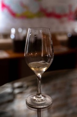 Wine tasting in underground cellars caves of French wine domain in Puligny-Motrachet village, Burgundy, France with map of Burgundy wine appelations and soils on background.