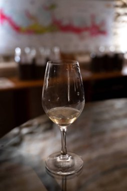 Wine tasting in underground cellars caves of French wine domain in Puligny-Motrachet village, Burgundy, France with map of Burgundy wine appelations and soils on background.
