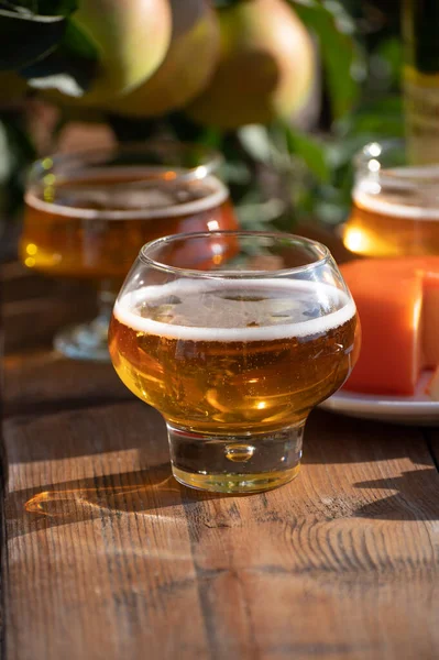 Food and drink pairing, apple cider in glasses produced on organic farm from bio apples in Normandy, France and farmers cheddar cheese from England