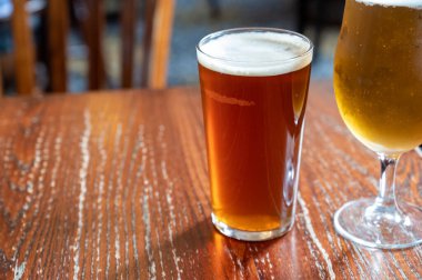 Pint glasses of cold fresh british ale and lager beer served in old vintage English pub