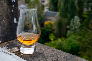 Glass of single malt scotch whisky served on old window sill in Scottisch house with view on old part of Edinburgh city, Scotland, UK, dram of blended whiskey