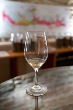 Wine tasting in underground cellars caves of French wine domain in Puligny-Motrachet village, Burgundy, France with map of Burgundy wine appelations and soils on background.