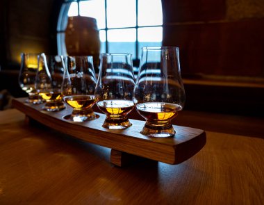 Flight of single malt scotch whisky in glasses served in bar in Edinburgh, UK, tasting of dram of whiskey