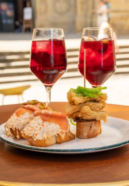 Glasses of cold sangria wine served outdoor with pinchos tapas in bar with view on old street in San Sebastian, Basque Country, Spain in summer