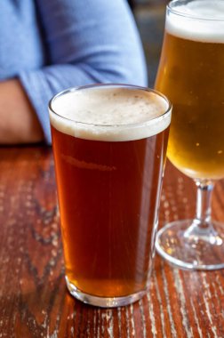 Pint glasses of cold fresh british ale and lager beer served in old vintage English pub