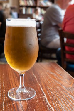Pint glass of british light pilsner ot lager beer served in old vintage English pub, close up