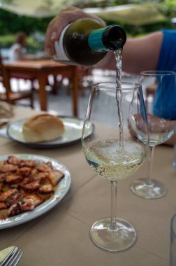 Pouring of txakoli or chacol slightly sparkling very dry white wine produced in Spanish Basque Country, served outdoor with view on Bay of Biscay, Atlantic Ocean