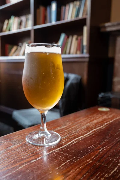 Pint glass of british light pilsner ot lager beer served in old vintage English pub, close up