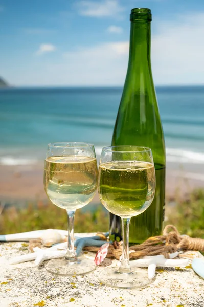 Pouring of txakoli or chacol slightly sparkling very dry white wine produced in Spanish Basque Country, served outdoor with view on Bay of Biscay, Atlantic Ocean