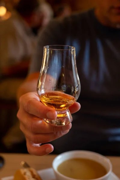Tasting of single malt scotch whisky in scottish bar in Edinburgh, UK, hand with glass of whisky