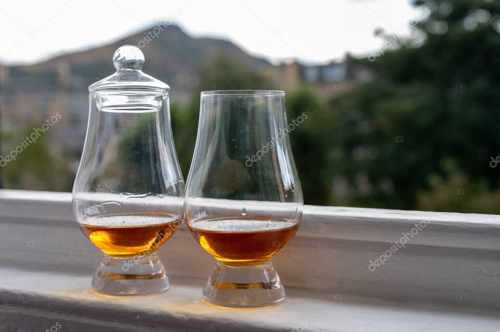 Two glasses of single malt scotch whisky served on old window sill in Scottisch house with view on old part of Edinburgh, Scotland, UK, dram of whiskey