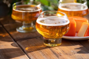 Food and drink pairing, apple cider in glasses produced on organic farm from bio apples in Normandy, France and farmers cheddar cheese from England