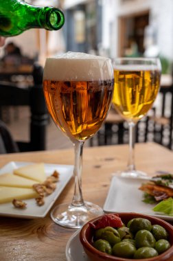 İspanyol açık hava kafesinde soğuk birayla öğle yemeği, yeşil zeytinli tapas kasesi ve fındıklı İspanyol peynirli manchego, Malaga, Endülüs...