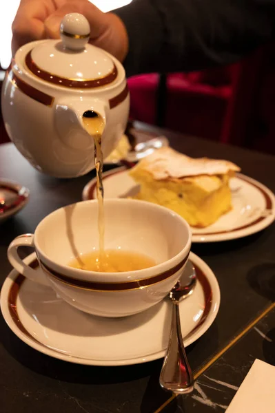 Tea time in England, pouring of black earl grey tea with bergamot in cup, high tea served cafe in London, close up