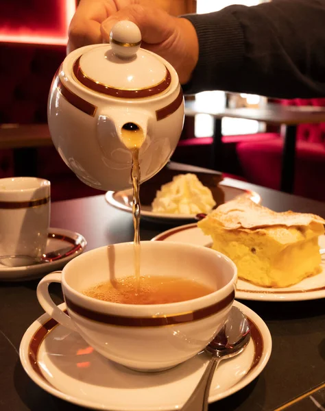 Tea time in England, pouring of black earl grey tea with bergamot in cup, high tea served cafe in London, close up