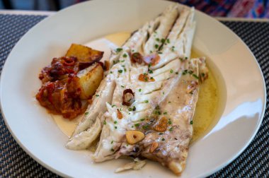 Eski kömür parillası üzerinde sarımsak ve zeytinyağıyla ızgara edilmiş taze balık lokantasında küçük balıkçı köyü Getaria 'da beyaz levrek balığı yemek.