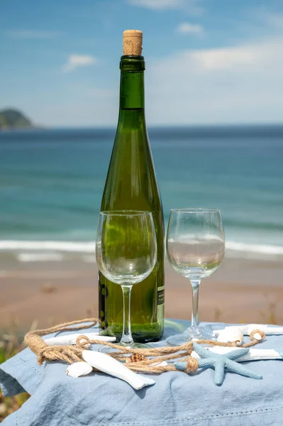 Tasting of txakoli or chacol slightly sparkling very dry white wine produced in Spanish Basque Country, served outdoor with view on Bay of Biscay, Atlantic Ocean