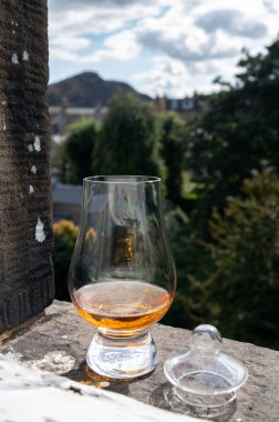 Glass of single malt scotch whisky served on old window sill in Scottisch house with view on old part of Edinburgh city, Scotland, UK, dram of blended whiskey