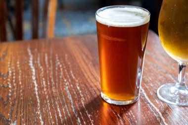 Pint glasses of cold fresh british ale and lager beer served in old vintage English pub