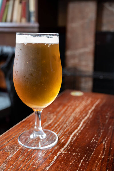 Pint glass of british light pilsner ot lager beer served in old vintage English pub, close up