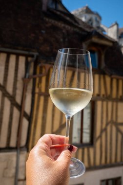 Tasting of white grand cru classe chablis wine with old French houses on background, Burgundy, wine tour is France