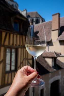 Tasting of white grand cru classe chablis wine with old French houses on background, Burgundy, wine tour is France