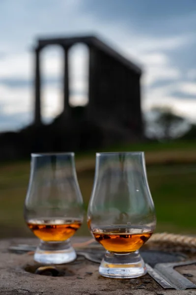 Tasting of single malt scotch whisky in glasses with panoramic view from Calton hill to new and old parts of Edinburgh city in rainy summer day, Scotland, UK