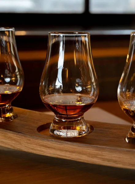 Flight of single malt scotch whisky in glasses served in bar in Edinburgh, UK, tasting of dram of whiskey