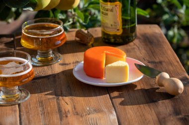 Food and drink pairing, apple cider in glasses produced on organic farm from bio apples in Normandy, France and farmers cheddar cheese from England