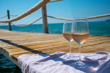 Provence 'den getirilen soğuk gül şarabı, mavi deniz manzaralı ahşap yat rıhtımında ve Saint-Tropez yakınlarındaki plaj plajında sergileniyordu.