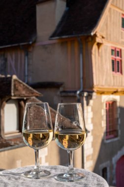 Tasting of white grand cru classe chablis wine with old French houses on background, Burgundy, wine tour is France