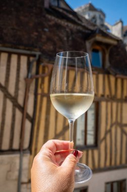 Tasting of white grand cru classe chablis wine with old French houses on background, Burgundy, wine tour is France