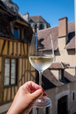 Tasting of white grand cru classe chablis wine with old French houses on background, Burgundy, wine tour is France
