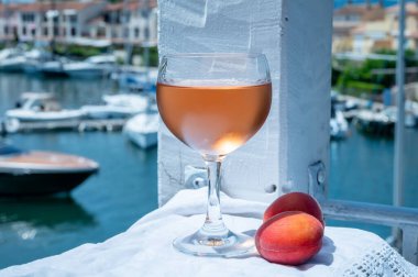 Drinking of cold rose wine from Provence with red apricots and view on yacht harbour of Port Grimaud, summer vacation on French Riviera, France